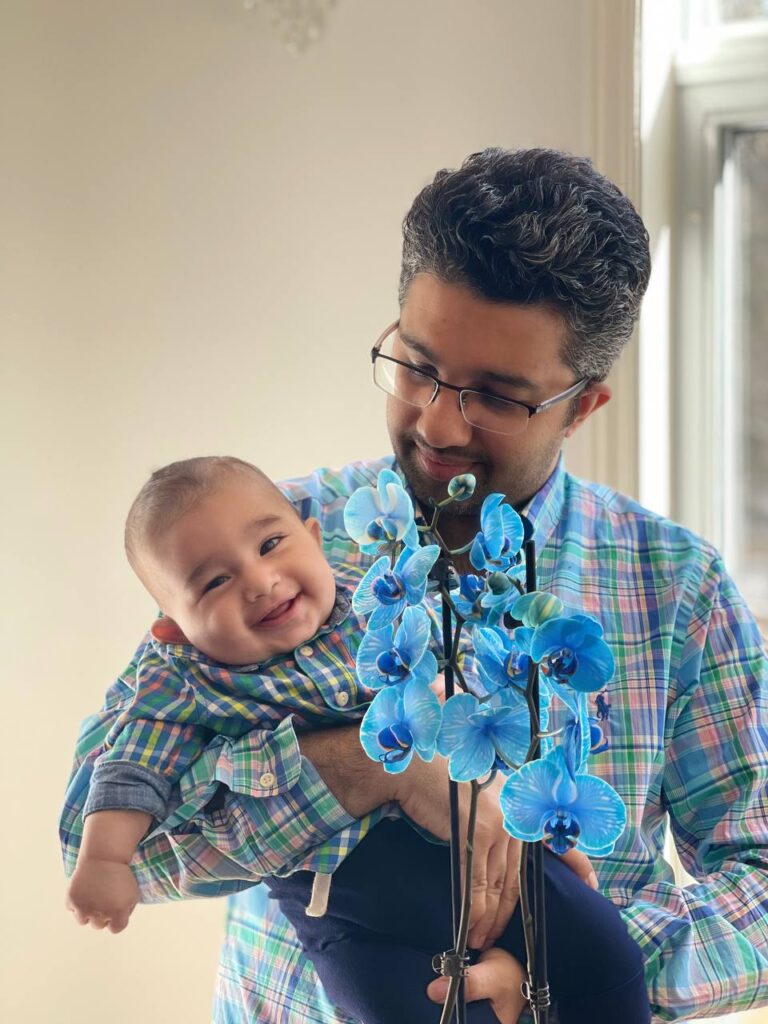 An image of a father with his infant son both wearing blue shirts.